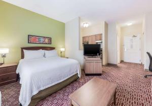 um quarto de hotel com uma cama e uma televisão de ecrã plano em Birch Hills Suites - Blue Ash em Blue Ash