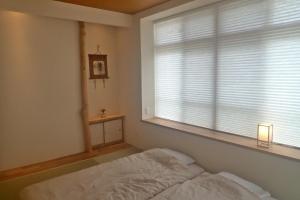 a bedroom with a bed and a window with blinds at Guest House Ishigaki in Ishigaki Island