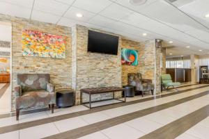 a lobby with chairs and a tv on a brick wall at Quality Inn Airport South in Charlotte