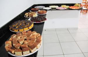 una mesa llena de diferentes tipos de pasteles y postres en Pousada das Letras, en São Thomé das Letras