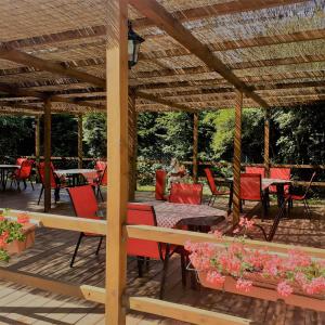 eine hölzerne Pergola mit roten Stühlen und Tischen in der Unterkunft Guesthouse Arnika in Fužine