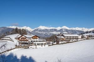 a house on a snowy hill with mountains in the background at Hotel Torgglerhof in Bressanone