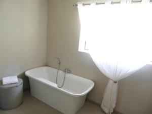 a white bath tub in a bathroom with a window at Oranje Guest Farm in Fouriesburg