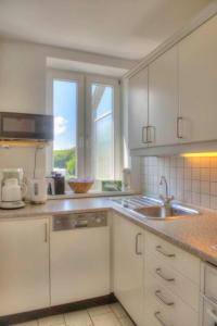 eine Küche mit weißen Schränken und einer Spüle und einem Fenster in der Unterkunft Zinnowitz Haus Zur Duene Wohnung 14 W14ZDL in Zinnowitz