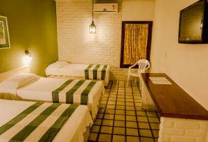 a hotel room with two beds and a desk at Hotel Casa Grande Gravatá in Gravatá