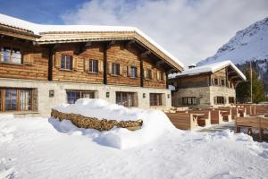 una cabaña de madera con una pila de nieve delante de ella en Berghuus Radons, en Savognin