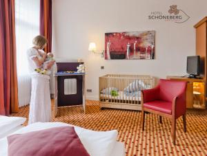 a woman holding a baby in a room with a crib at Hotel Schöneberg in Berlin