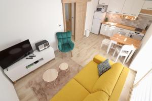 a living room with a yellow couch and a kitchen at Chata Matzo in Mýto pod Ďumbierom