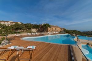 a large swimming pool with chairs and a wooden deck at Hotel Borgo Smeraldo in Arzachena