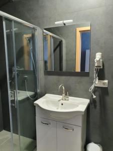 La salle de bains est pourvue d'un lavabo et d'une douche. dans l'établissement Hotel Schneider Apartaments, à Langenhagen