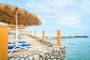 Sunrise Diamond Beach Resort -Grand Select في شرم الشيخ: شاطئ به كراسي ومظلة من القش والماء