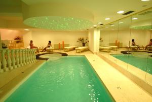 una piscina en el vestíbulo del hotel con personas sentadas en bancos en Isabel en Pinzolo