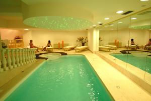 a swimming pool in a hotel lobby with people sitting on benches at Isabel in Pinzolo