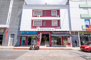 a red and white building with a motorcycle parked in front at Hotel El Principe in Bucaramanga