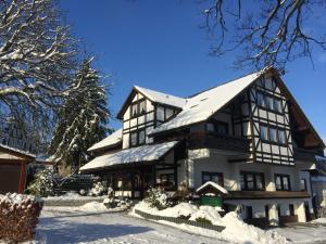 a large black and white building in the snow at Hotel Pension Berghaus Sieben in Bad Laasphe