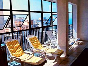 three chairs on a balcony with a view of the city at Flat Capitania em Pitangueiras perto da praia in Guarujá