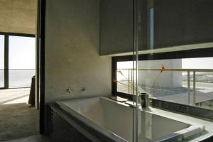 a bathroom with a large tub and a window at VAME Beachfront in Yzerfontein