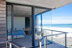 a bedroom with a bed and a view of the beach at VAME Beachfront in Yzerfontein