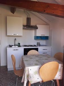 eine Küche mit einem Tisch und Stühlen sowie eine Küche mit weißen Schränken in der Unterkunft Villa Peachey (Picci), Grazioso Appartamento in Stresa