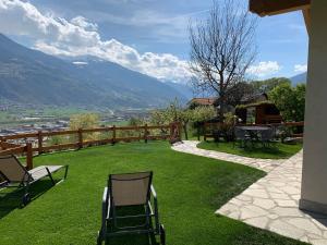 a patio with chairs and a table on the grass at L'armonia della natura in Aosta