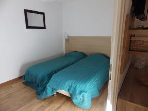 un letto con lenzuola blu in una piccola stanza di Appartement Les Jardins de Ramel 2 a Luchon