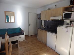 a small kitchen with a refrigerator and a table at Appartement Les Jardins de Ramel 2 in Luchon