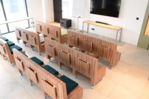 a row of wooden benches in a room with a tv at Live Hotels Bordeaux Lac in Bordeaux