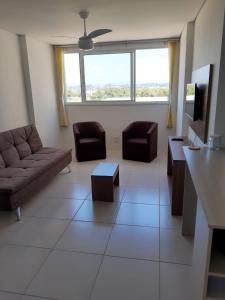 a living room with a couch and chairs and a tv at Apartamento em ótima localização in Torres