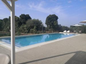 een zwembad met twee witte stoelen ernaast bij Dimora di Dante in Chiaramonte Gulfi