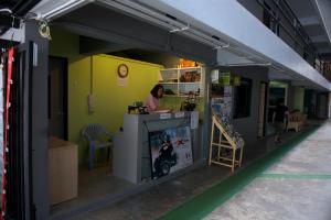 a woman is sitting at a counter in a store at 9 Hostel in Chiang Mai