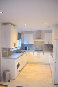 een keuken met witte kasten en een wasmachine bij 3 Bedroom-Kelpies Serviced Apartments Bruce in Falkirk