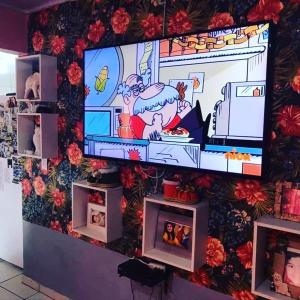 a wall with a tv in a room with flowers at Residencial Segundo Piso in Garopaba