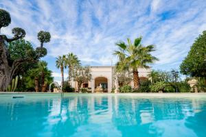 a swimming pool in front of a house with palm trees at Villa Tonia in Fasano