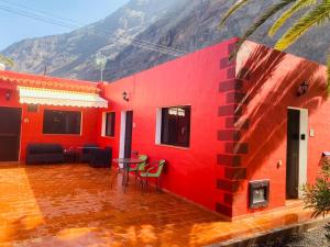 Casa roja con mesa, sillas y montaña en Pensión Casa Trudo, en La Frontera