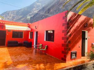 a red house with a table and chairs and a mountain at Pensión Casa Trudo in Frontera