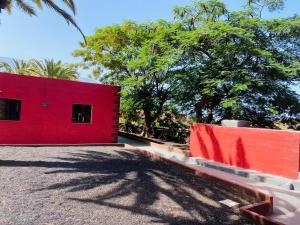 a red building with a red wall and trees at Pensión Casa Trudo in Frontera