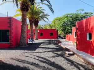 un edificio rojo con palmeras delante en Pensión Casa Trudo, en La Frontera