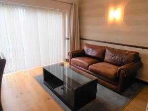 a living room with a leather couch and a glass coffee table at Hollies Hotel in Martock