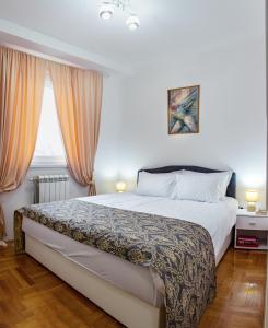 a bedroom with a large bed and two windows at Apartman Mia in Sremska Mitrovica