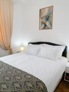 Un dormitorio con una cama blanca con una foto en la pared en Apartman Mia en Sremska Mitrovica