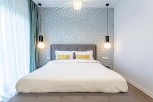 una camera da letto con un grande letto bianco con cuscini gialli di Il Lago - Sunrise - Cozy Luxurious Smart Home By The Lake a Voluntari