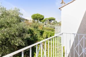 Casa blanca con barandilla blanca y árboles en Maison La Fontonne - Welkeys, en Antibes