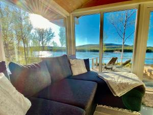 - un salon avec un canapé et une grande fenêtre dans l'établissement Aurora mökki porealtaalla Lapissa Tenojoen rannassa, à Nuorgam