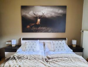 ein Schlafzimmer mit einem Bett mit einem Hirschgemälde an der Wand in der Unterkunft Kitzbühel Apartments Haus Brugger in Kitzbühel