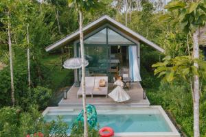 Ein kleines Mädchen steht auf einem Deck neben einem Pool in der Unterkunft Island Escape Burasari in Phuket