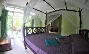 a bedroom with a canopy bed with a purple comforter at The Spice House Mirissa in Mirissa