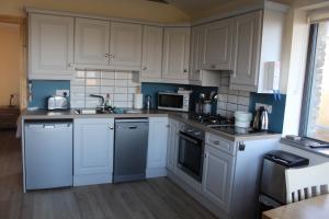 a kitchen with white cabinets and a stove top oven at The Stable Self Catering Cottage @ Cappa House BnB in Eyeries