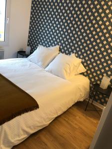een bed met witte lakens en kussens in een slaapkamer bij Le Gîte du Jard in Épernay