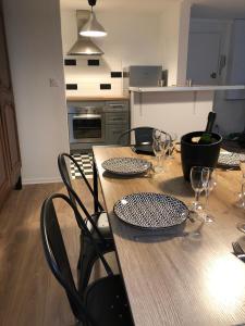 a wooden table with chairs and wine glasses on it at Le Gîte du Jard in Épernay