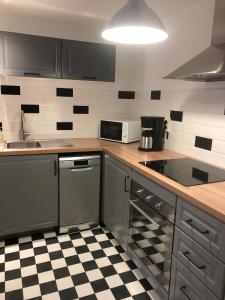 uma cozinha com electrodomésticos em aço inoxidável e um piso em xadrez em Le Gîte du Jard em Épernay
